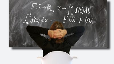 学生在明亮教室内认真听课，黑板上写满公式，阳光从窗户透入